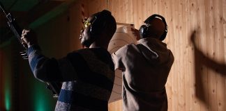 Un homme tient un fusil et profite d'une séance de tir récréative dans un stand de tir, entouré d'un groupe d'amis. Des personnes s'entraînent au maniement des armes dans un environnement sécurisé au sein d'un stand de tir.